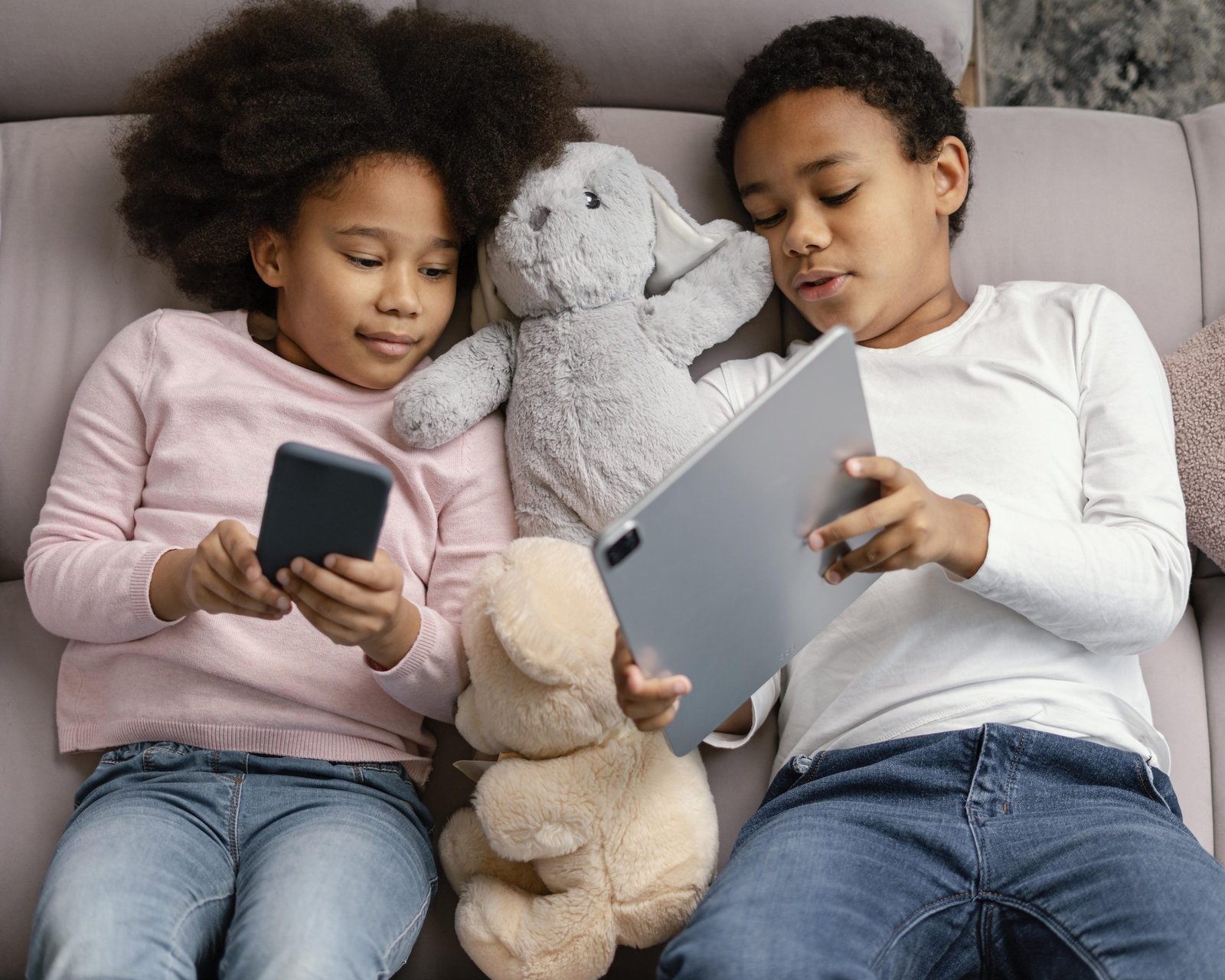 Deux enfants partageant un téléphone et une tablette