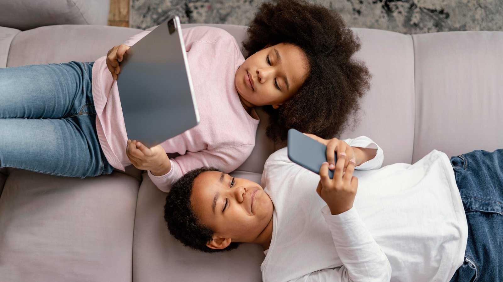 Deux enfants découvrant une tablette et un smartphone