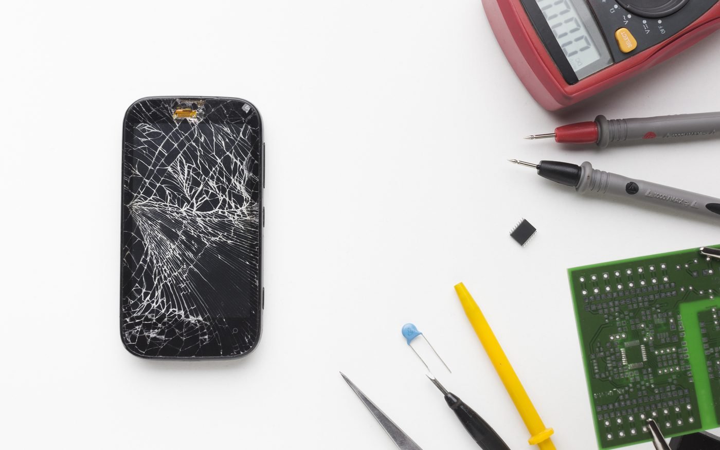 Écran de smartphone cassé entouré d'outils de réparation